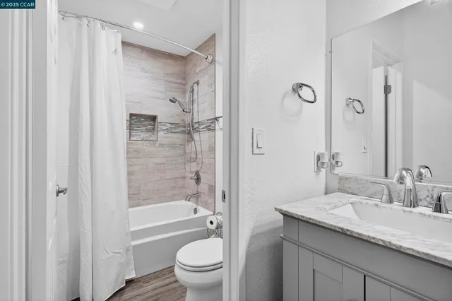 a bathroom with a granite countertop sink a toilet and shower