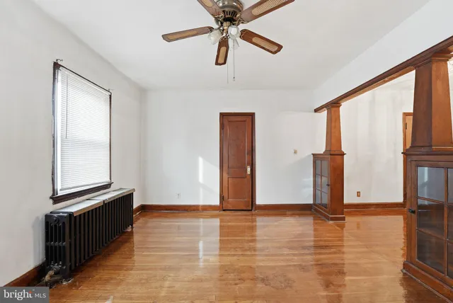 a view of an empty room with window and wooden floor