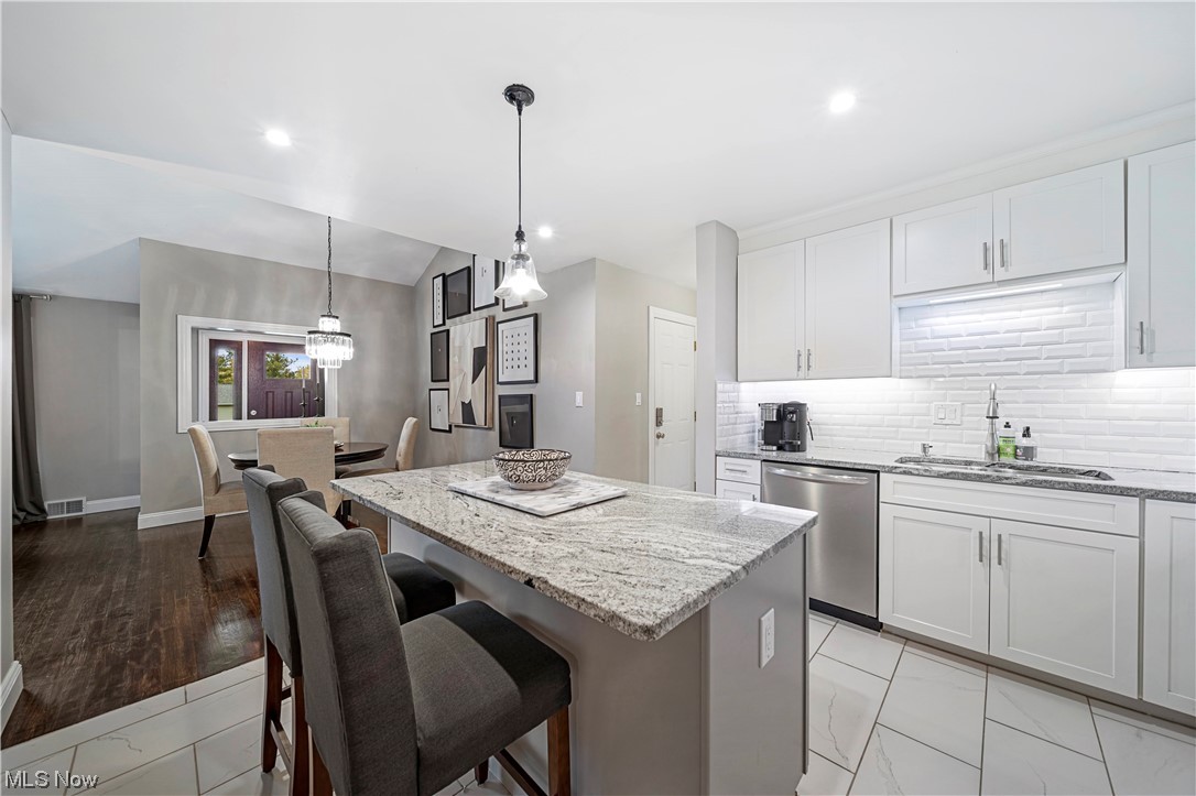 6258 Fairhaven Road Cleveland, OH 44124 - Photo 2 of 35 Kitchen with stainless steel dishwasher, island, tasteful backsplash, hanging light fixtures, and white cabinets