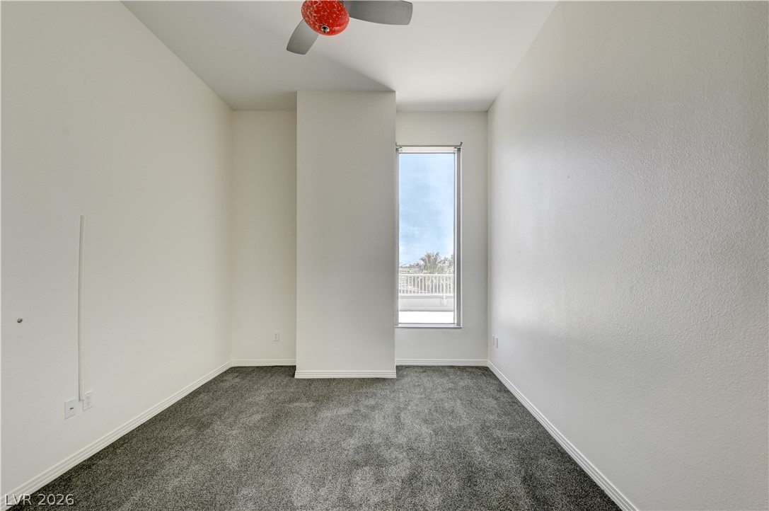 360 East Desert Inn Road, Unit 402 Las Vegas, NV 89109 - Photo 33 of 40 A well-lit bedroom with fresh gray carpeting and a tall window.