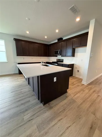 a large kitchen with kitchen island a sink wooden floor and a refrigerator