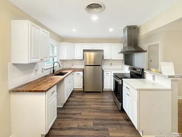 a kitchen with a sink stainless steel appliances white cabinets and a window