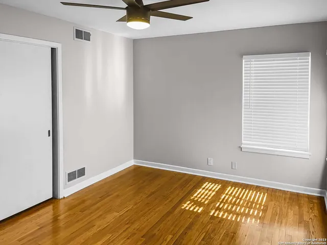 a view of an empty room with wooden floor and a window