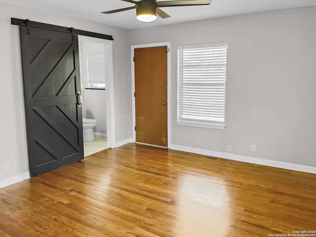 a view of an empty room with wooden floor and a window