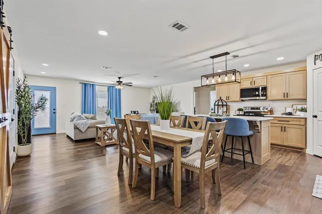 a kitchen with stainless steel appliances a table chairs refrigerator and cabinets