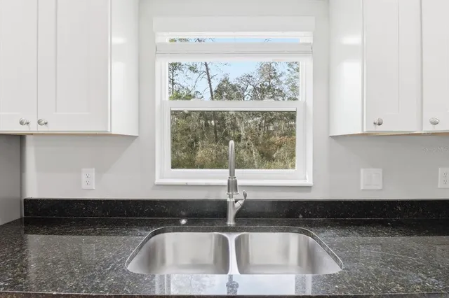 a kitchen with granite countertop white cabinets and a sink