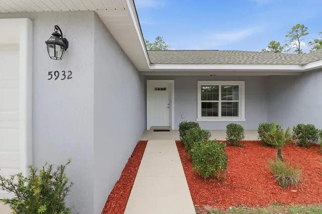 a front view of a house with a yard and potted plants