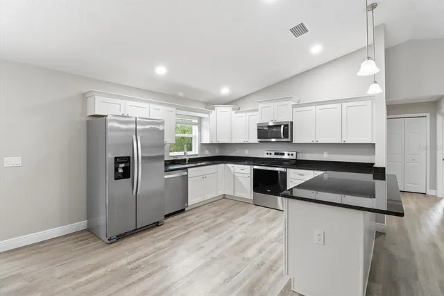 a kitchen with granite countertop a refrigerator and a sink