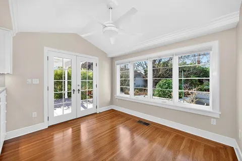 an empty room with wooden floor fireplace and windows