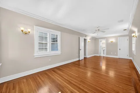 a view of an empty room with wooden floor and a bathroom