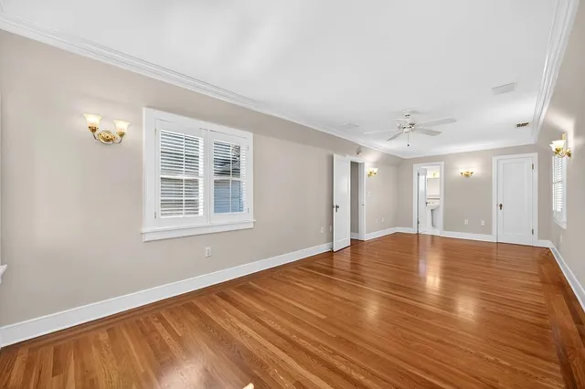 a view of an empty room with wooden floor and a bathroom