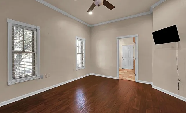 a view of empty room with wooden floor and fan