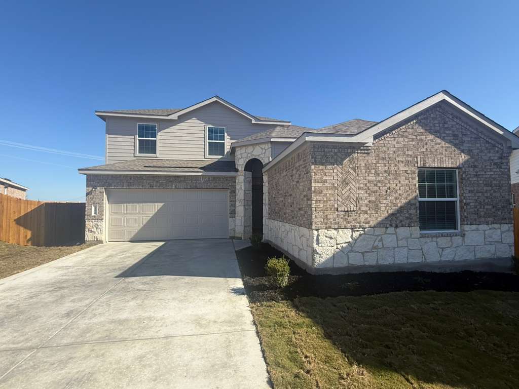 View of front facade with driveway, an attached garage, roof with shingles, and brick siding