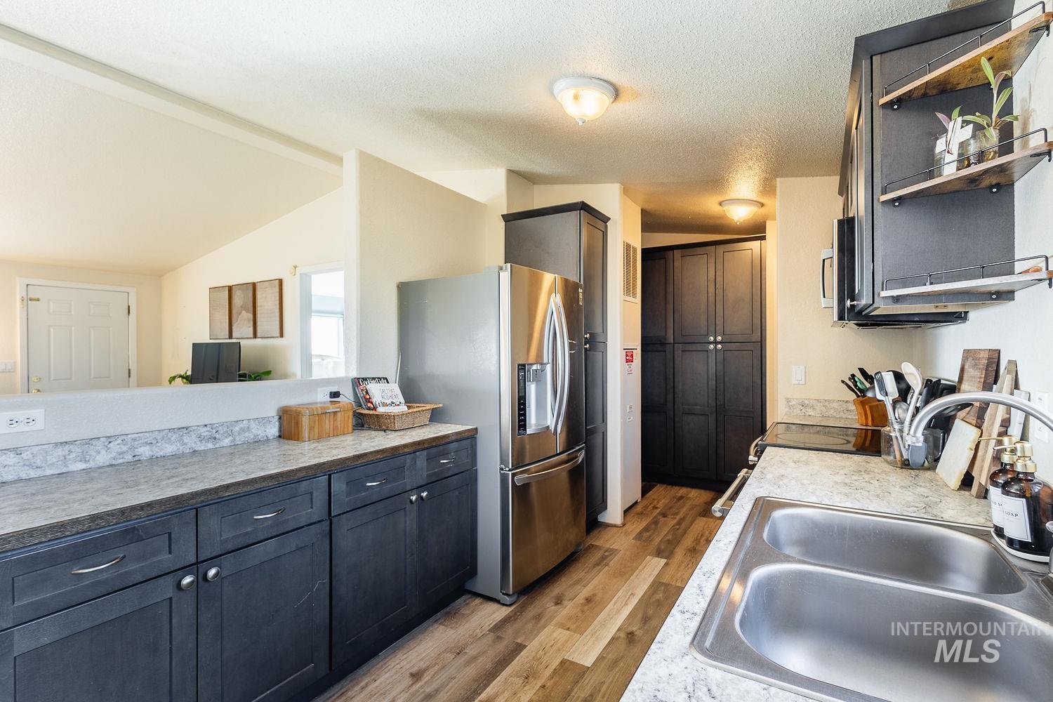 21568 Market Road Parma, ID 83660 - Photo 7 of 22 Kitchen featuring light wood-type flooring, stainless steel appliances, open shelves, and light countertops