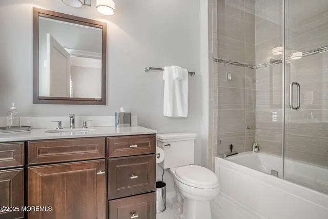 a bathroom with a toilet sink vanity tub and mirror