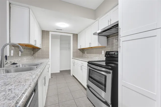 a kitchen with granite countertop a sink stove and cabinets