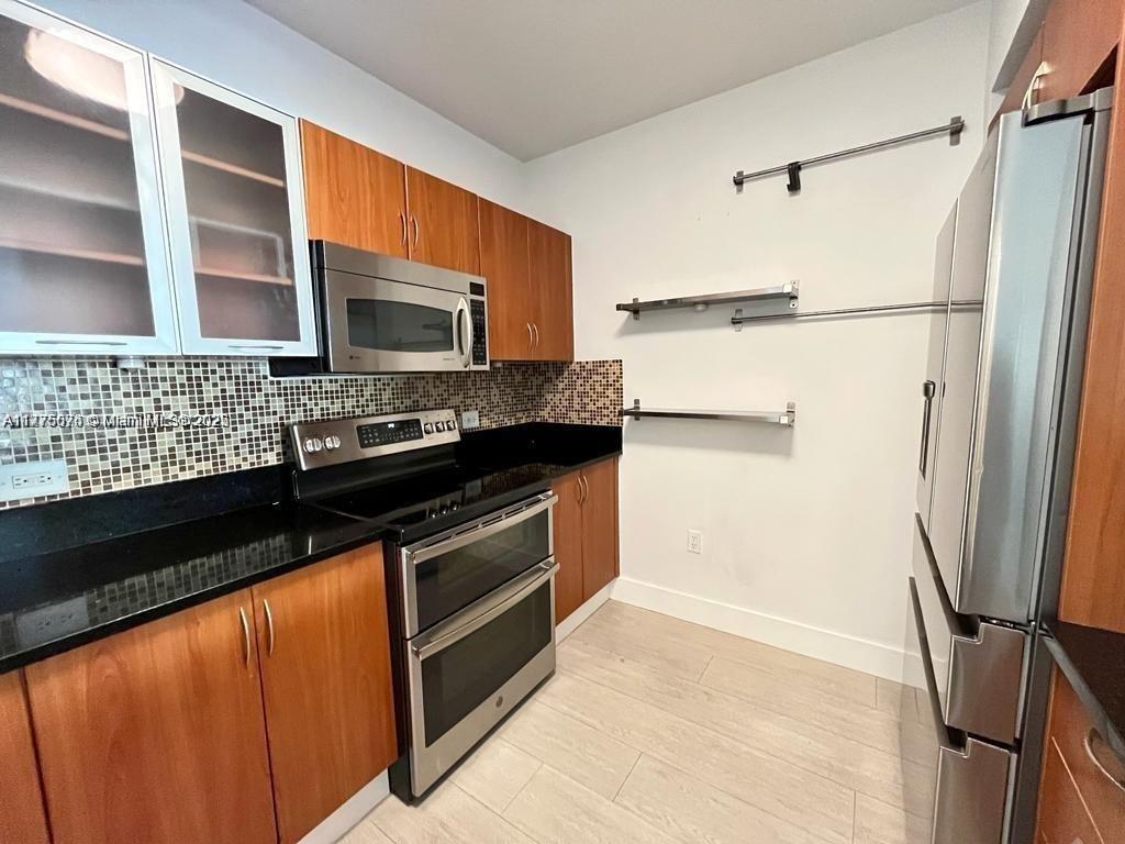 2775 Northeast 187th Street, Unit 326 Aventura, FL 33180 - Photo 11 of 23 a kitchen with granite countertop a refrigerator and a stove top oven