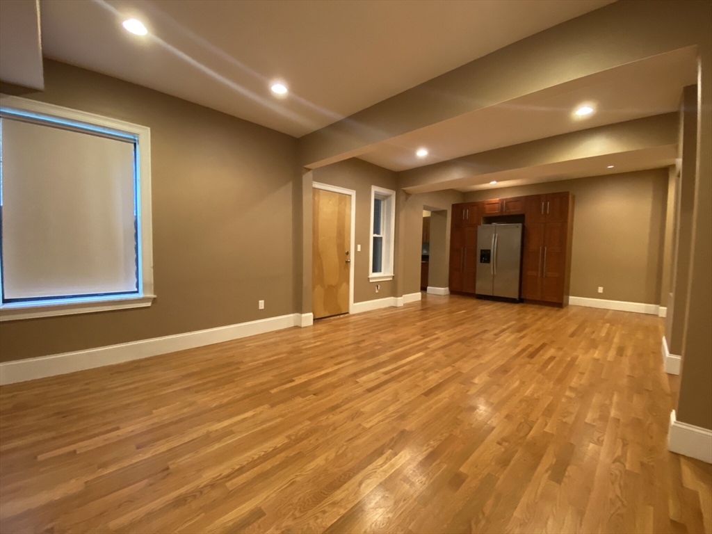 1592 Beacon Street, Unit 3 Brookline, MA 02446 - Photo 3 of 10 a view of an empty room with wooden floor and a window