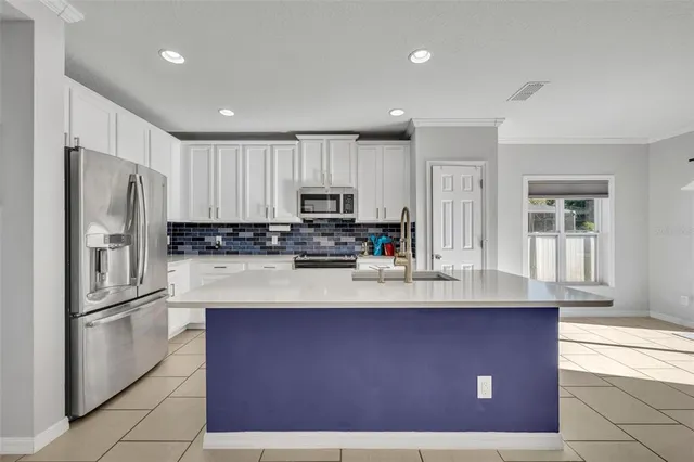 a kitchen with kitchen island a counter top space cabinets and stainless steel appliances