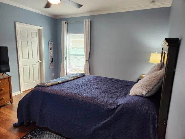 a bedroom with a bed tv and wooden floor