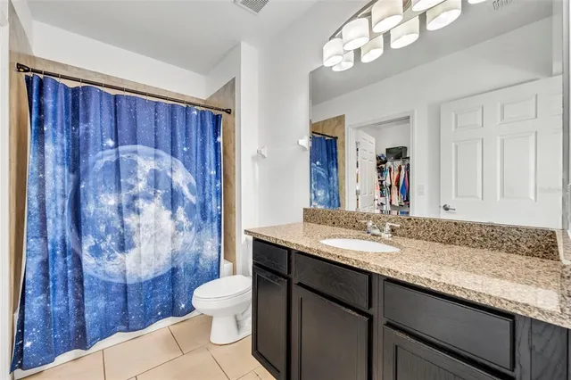 a bathroom with a granite countertop sink a toilet and a mirror