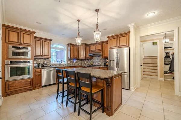 a kitchen with stainless steel appliances granite countertop a stove a refrigerator a oven a sink with a dining table and chairs