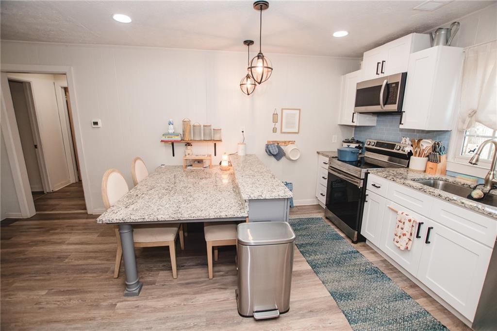 721 Davis Street Monroe, GA 30655 - Photo 9 of 20 a kitchen with granite countertop a table chairs microwave and refrigerator