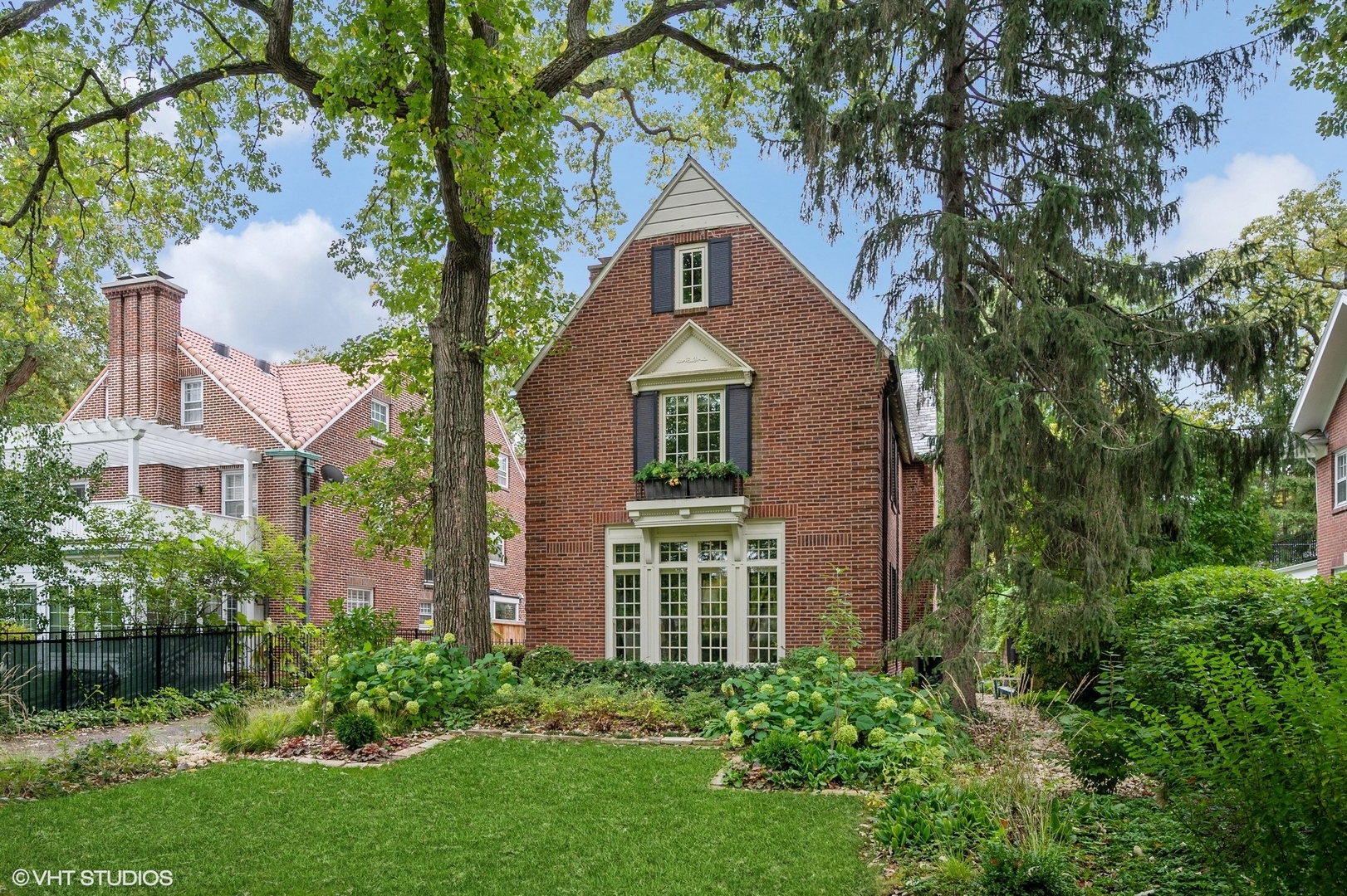 354 Elder Lane Winnetka, IL 60093 - Photo 2 of 71 a view of a brick house with a large windows and a yard with plants and large trees