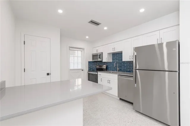 a kitchen with refrigerator and white cabinets