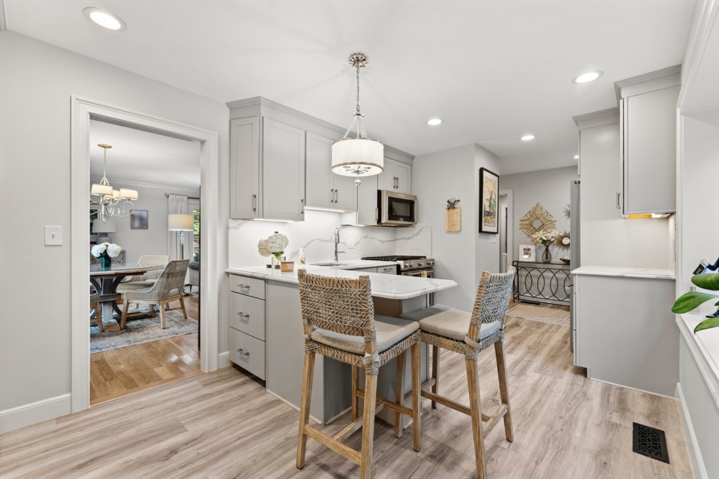 16 Preacher Road, Unit 16 Milton, MA 02186 - Photo 5 of 32 a kitchen with granite countertop a stove a sink dishwasher a refrigerator and white cabinets with wooden floor