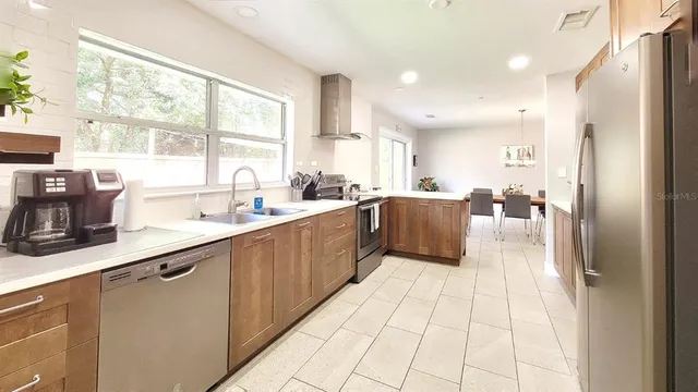 a large kitchen with stainless steel appliances a sink large window and counter space
