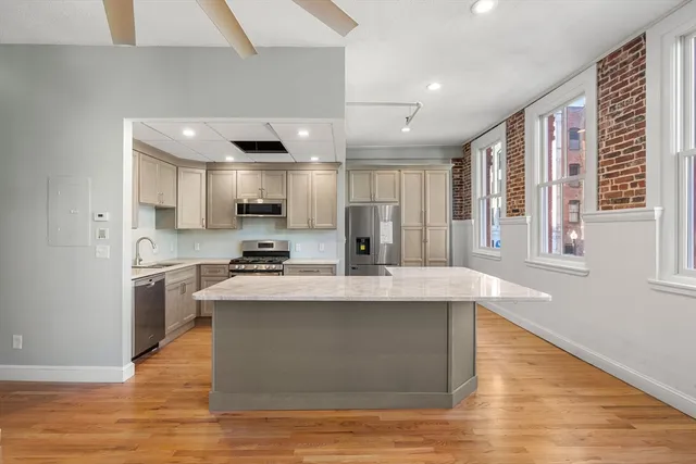 a large white kitchen with kitchen island a stove a sink dishwasher and a dining table with wooden floor