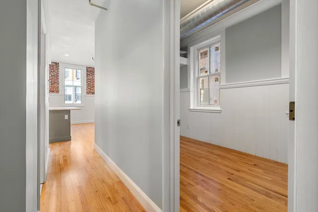 a view of a hallway with wooden floor and a bathroom