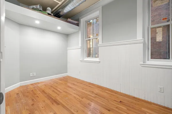 an empty room with wooden floor and windows