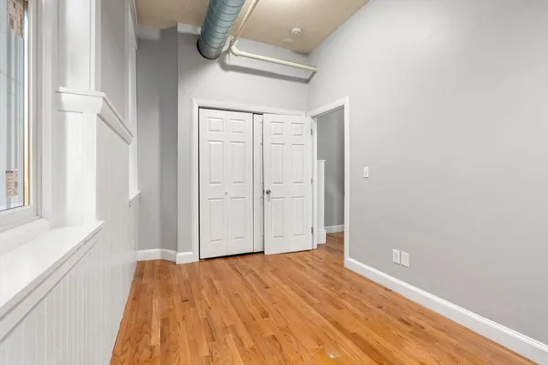 a view of empty room with wooden floor and fan