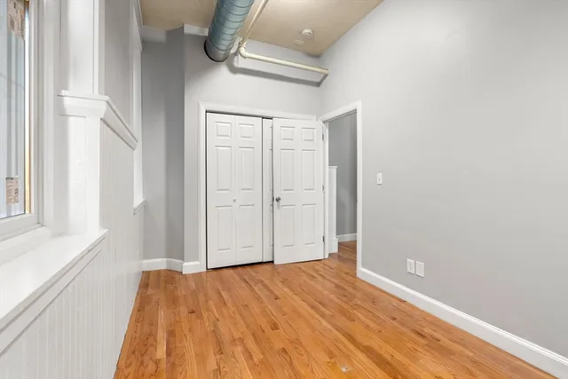 a view of empty room with wooden floor and fan