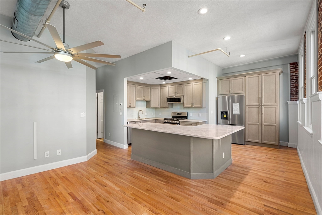 62 Washington Street, Unit 5 Haverhill, MA 01832 - Photo 3 of 34 a large kitchen with stainless steel appliances a large counter top a sink a stove and a refrigerator