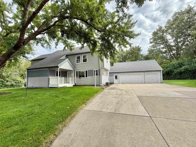 a view of a house with a yard and large trees