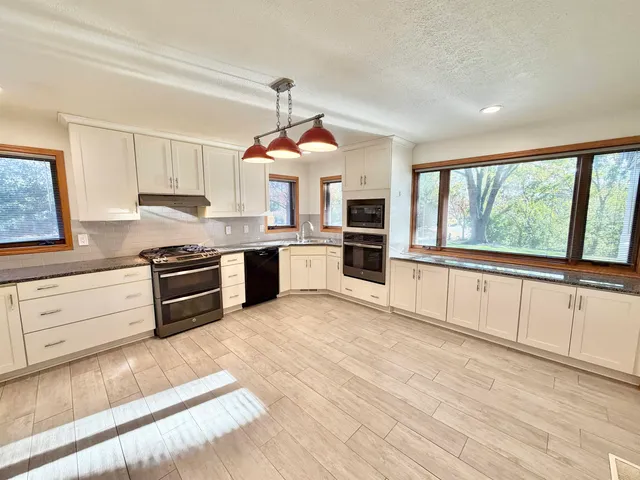 a kitchen with granite countertop a stove cabinets and refrigerator