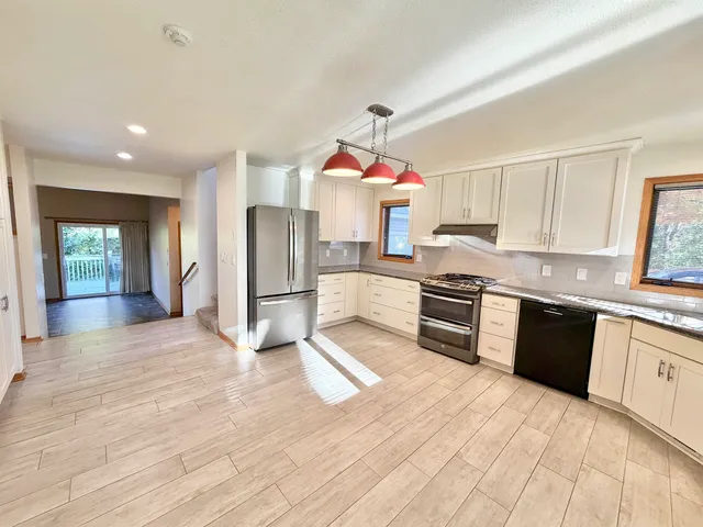 a large kitchen with stainless steel appliances granite countertop a stove a sink and dishwasher