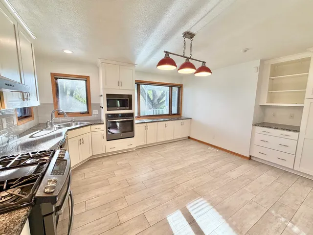 a kitchen with granite countertop white cabinets and appliances