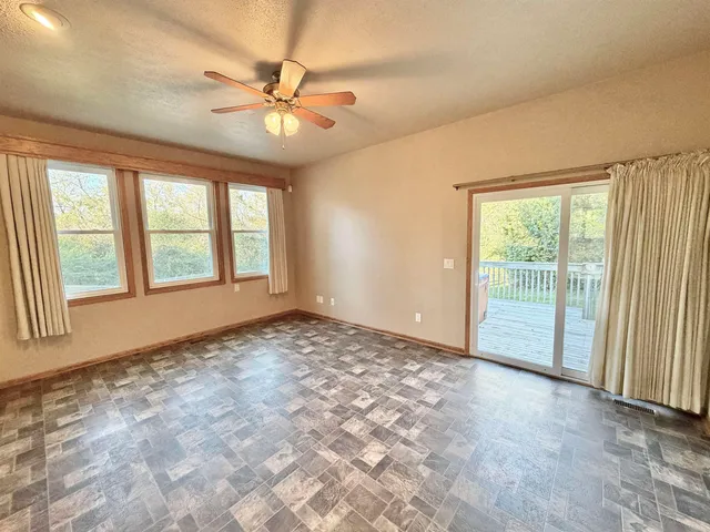 an empty room with a window and a ceiling fan
