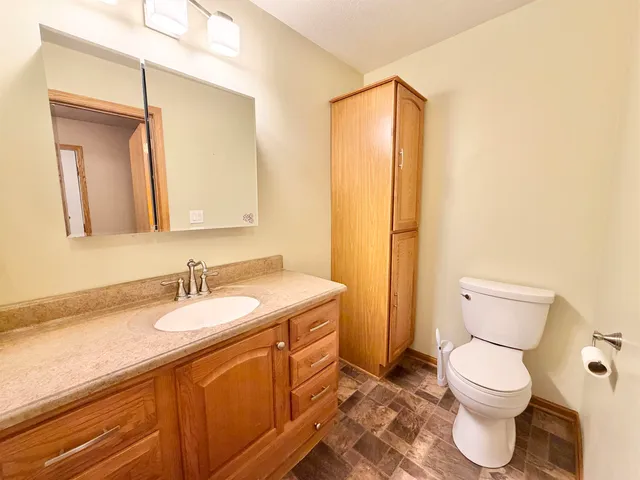 a bathroom with a granite countertop toilet sink mirror and vanity
