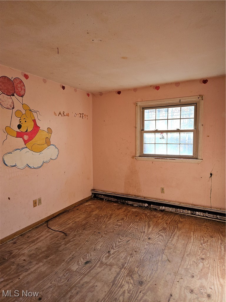 16940 Thompson Road Thompson, OH 44086 - Photo 8 of 30 Empty room featuring wood-type flooring and a baseboard heating unit