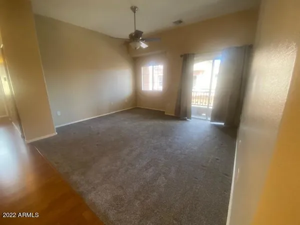 an empty room with windows and chandelier fan