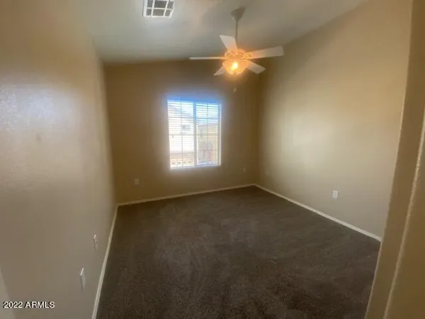 an empty room with a chandelier fan and window
