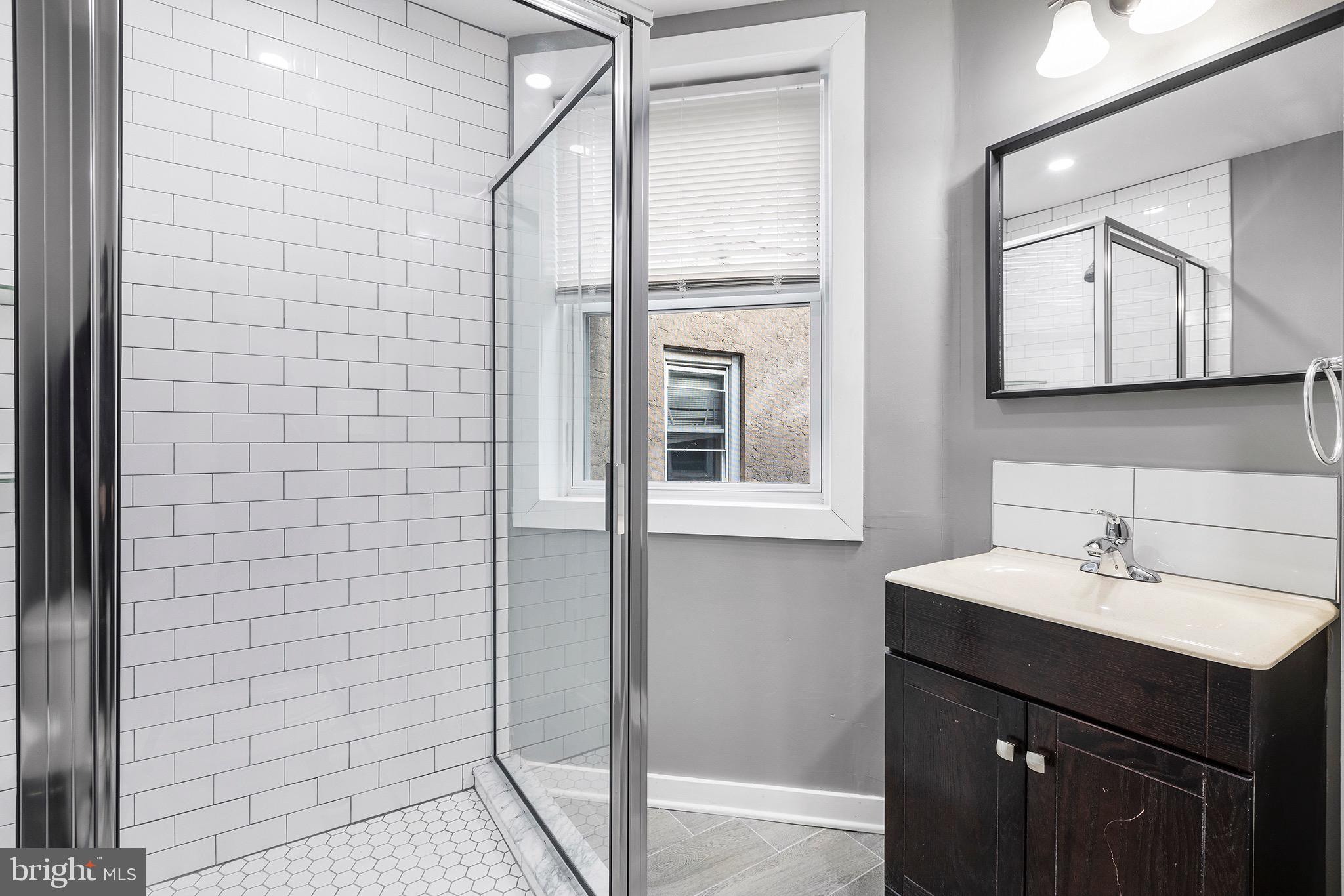 2125 North 20th Street, Unit 2 Philadelphia, PA 19121 - Photo 6 of 20 a bathroom with a sink a mirror and a shower