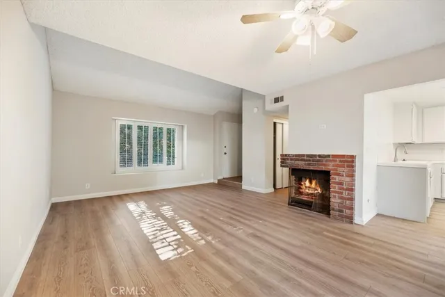 an empty room with windows a fireplace and wooden floor