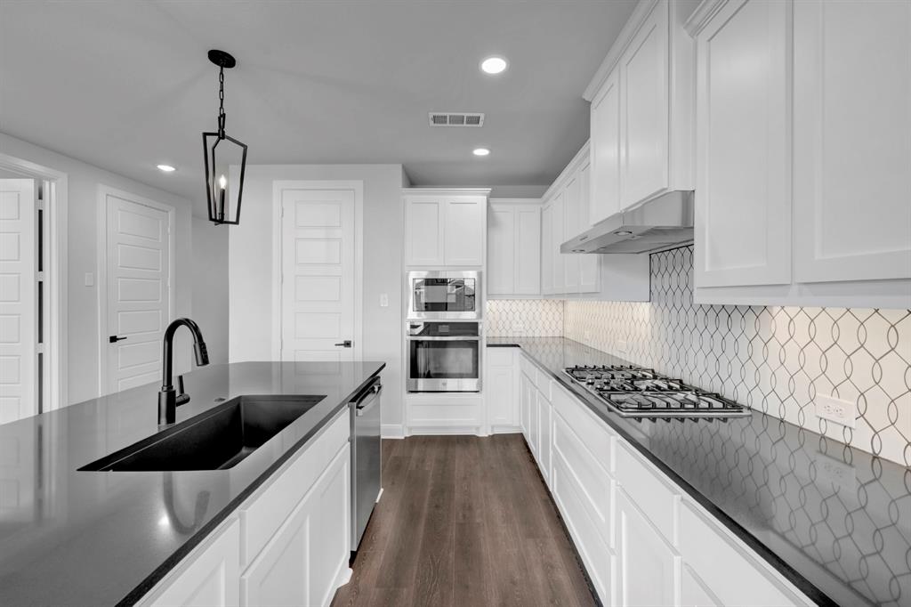 9004 Chestnut Lane Justin, TX 76247 - Photo 23 of 40 a kitchen with kitchen island stainless steel appliances a sink stove and cabinets