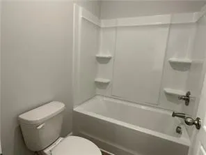 a white toilet sitting next to a bath tub